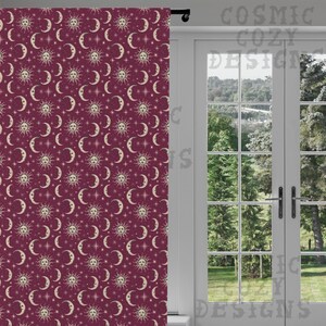 May include: A burgundy curtain with a repeating pattern of suns, crescent moons, and stars in cream. The curtain is hanging in front of a white door with a view of trees and a grassy area. The text "COSMIC COZY DESIGNS" is visible.