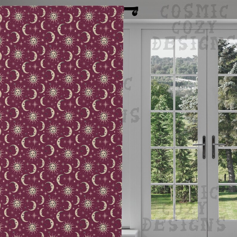 May include: A burgundy curtain with a repeating pattern of suns, crescent moons, and stars in cream. The curtain is hanging in front of a white door with a view of trees and a grassy area. The text "COSMIC COZY DESIGNS" is visible.