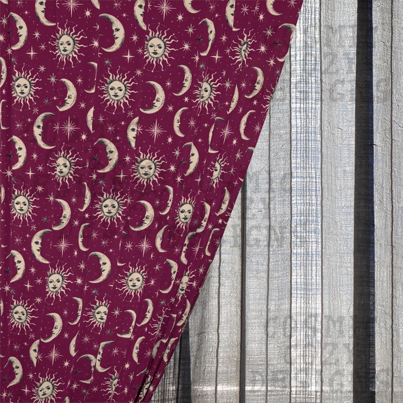 May include: A burgundy fabric with a celestial pattern of suns, moons, and stars. The design features cream-colored celestial bodies and stars against a dark red background. The fabric is partially covering a gray, vertical-striped surface.
