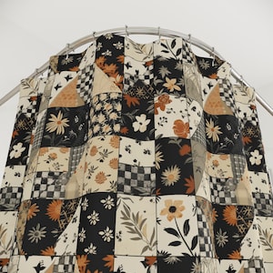 Könnte beinhalten: Ein Patchwork-Duschvorhang mit floralem und geometrischem Muster. Der Vorhang zeigt Quadrate aus schwarzem, cremefarbenem und beigem Stoff mit Gänseblümchen, Blättern und karierten Designs. Der Vorhang hängt an einer gebogenen Metallstange.