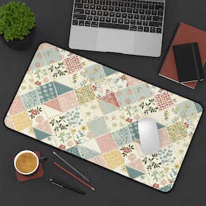 Peut inclure: Un tapis de souris rectangulaire avec un motif patchwork composé de motifs floraux et géométriques aux couleurs pastel. Le tapis a une bordure noire et est entouré d'un ordinateur portable, d'une tasse à café et de papeterie.