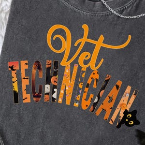 May include: A dark gray t-shirt with the words "Vet Technician" in orange script and block letters. The letters are filled with Halloween-themed images. A black cat and bats decorate the shirt.