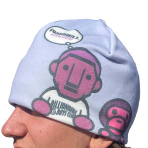May include: A light blue beanie featuring a cartoon graphic of a character with a pink face and a thought bubble that says "Pharrell In My Mind". The character is wearing a white shirt with the text "Billionaire Boys Club".