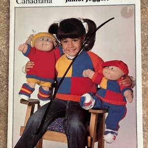 May include: A knitting pattern for "Junior Joggers" from Patons Canadiana. The pattern is number 1030 and costs $1.50. The pattern shows a girl wearing a red, yellow, and blue sweater with a matching pair of pants. She is holding two Cabbage Patch Kids dolls, one wearing a red, yellow, and blue sweater and the other wearing a red, yellow, and blue outfit.