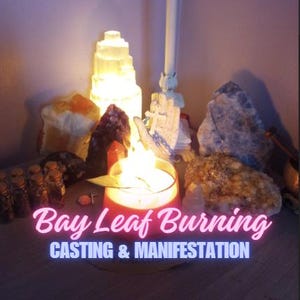 Op de afbeelding: Een brandende kaars in een rode glazen houder met een laurierblad bovenop, omringd door diverse kristallen, een witte torenlamp en kleine glazen flesjes. De tekst "Bay Leaf Burning" en "CASTING & MANIFESTATION" is over de afbeelding geplaatst.
