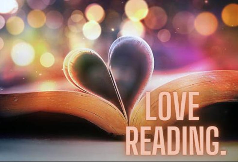 May include: An open book with its pages folded to form a heart shape. The text LOVE READING. is printed in a light peach color on the right side of the open pages. The background features soft, out-of-focus circular lights in warm tones.
