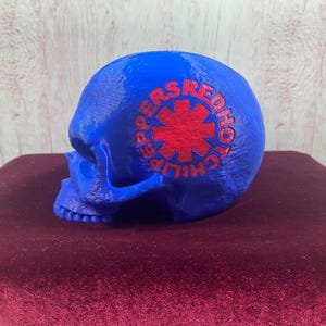 May include: A blue skull with a red chili pepper logo that says "Red Hot Chili Peppers" on the side.
