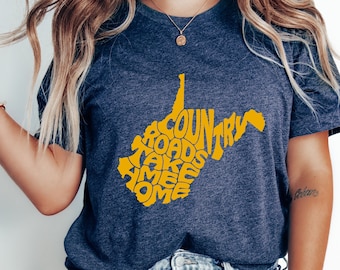 Puede incluir: Una camiseta azul marino jaspeada con un gráfico amarillo del estado de Virginia Occidental. El gráfico está formado por las palabras "Country Roads Take Me Home".