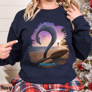 Puede incluir: Una sudadera azul marino con un gr&aacute;fico de un gancho y un barco de la pel&iacute;cula Moana 2. El gr&aacute;fico est&aacute; en un esquema de color blanco, azul y naranja.
