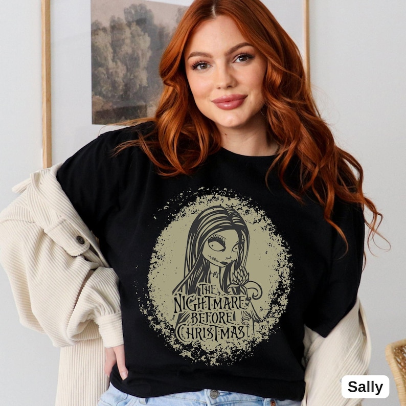 Puede incluir: Camiseta negra con un gr&aacute;fico circular beige desgastado que presenta una ilustraci&oacute;n en blanco y negro de Sally de "Pesadilla antes de Navidad" con el texto "The Nightmare Before Christmas".
