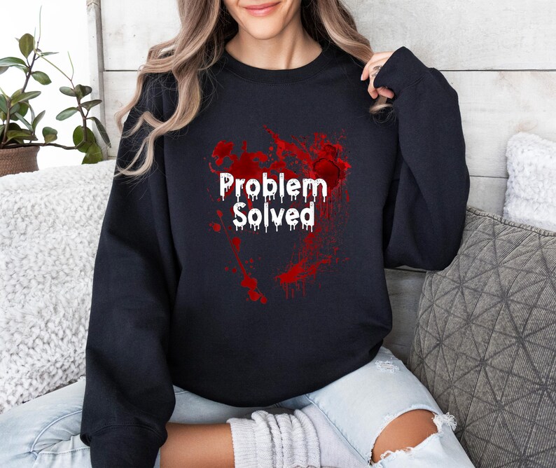Może przedstawiać: Czarna bluza z białym napisem "Problem Solved" w kroplowym kroju pisma. Tekst jest nałożony na czerwony wz&oacute;r rozprysk&oacute;w. Bluza ma swobodny styl.