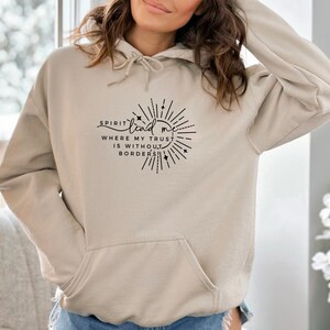 May include: A beige hoodie with a black graphic print that says "Spirit lead me where my trust is without borders". The graphic is a circle with a sunburst design and stars.