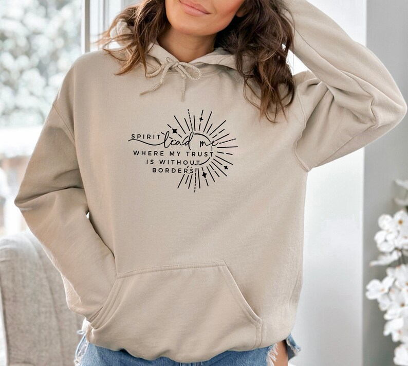 May include: A beige hoodie with a black graphic print that says "Spirit lead me where my trust is without borders". The graphic is a circle with a sunburst design and stars.