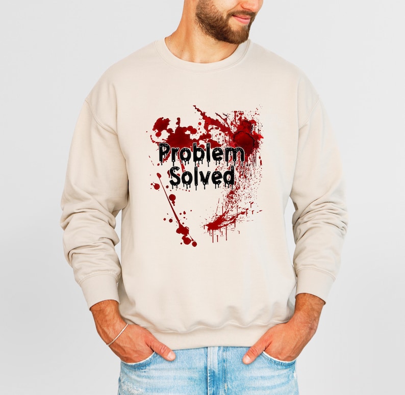 Może przedstawiać: Beżowa bluza z napisem "Problem Solved" w kolorze czarnym, nałożonym na czerwony wz&oacute;r rozprysk&oacute;w. Bluza w stylu casual, odpowiednia do noszenia na co dzień.
