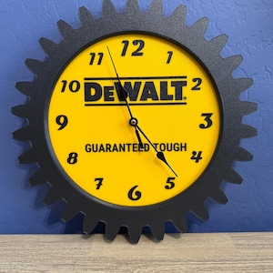 May include: A yellow and black clock with the "DEWALT" logo and the words "GUARANTEED TOUGH". The clock is shaped like a gear with black teeth around the yellow clock face. The clock hands are black.