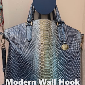 May include: A blue handbag with a snakeskin pattern is displayed on a modern wall hook. The bag has a gold-colored charm and handles. The text "Modern Wall Hook" is visible at the bottom of the image.