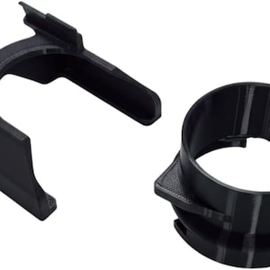 May include: Two black plastic automotive components are shown against a white backdrop. One is a bracket with a curved top and two angled extensions. The other is a circular ring with a square base and a lip.
