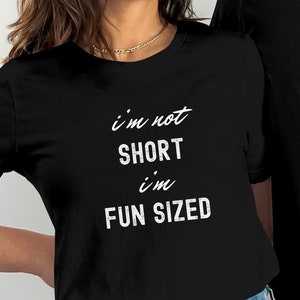 May include: Two black t-shirts with white text. The text on the left shirt reads "i'm not short i'm fun sized". The text on the right shirt reads "i'm not short i'm fun sized".