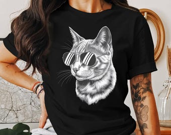 May include: Black t-shirt featuring a detailed grayscale illustration of a cat wearing sunglasses. The cat's fur is intricately shaded, and the sunglasses have a classic design. The shirt is a classic crew neck.