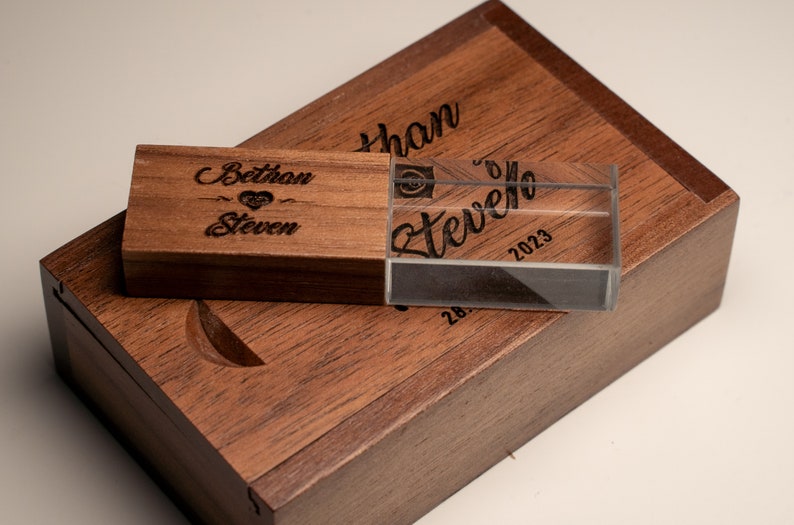 May include: A wooden box with a clear acrylic USB drive inside. The box and drive are engraved with the names "Bethany" and "Steven" and the date "2023".