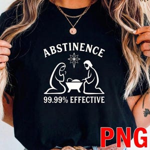 Könnte beinhalten: Schwarzes T-Shirt mit dem Wort "ABSTINENCE" über einer weißen Grafik der Krippenszene und dem Text "99,99% EFFECTIVE". Das T-Shirt hat einen Rundhalsausschnitt und kurze Ärmel.