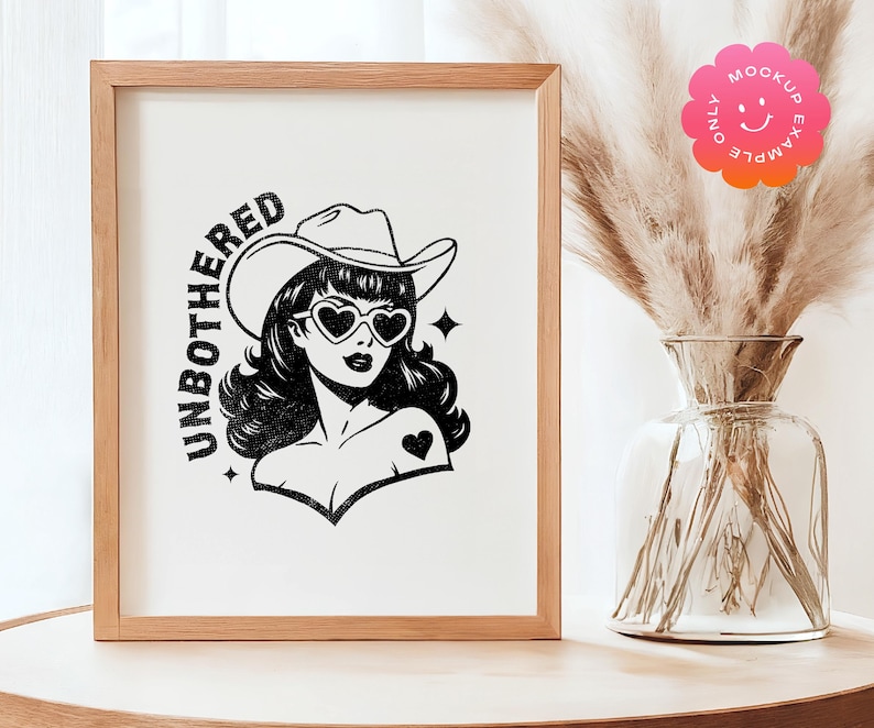 May include: A framed print with a black and white illustration of a woman wearing a cowboy hat and sunglasses. The text "UNBOTHERED" is written in a vintage style font.