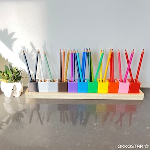 May include: A wooden pencil holder with 12 individual compartments, each holding a different colored pencil. The pencils are arranged in a rainbow pattern, with the colors red, orange, yellow, green, blue, indigo, and violet. The holder is made of natural wood and has a smooth finish.