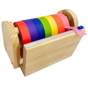 May include: Wooden tape dispenser with a rainbow assortment of washi tapes. The dispenser has a clear plastic lid and a wooden base.