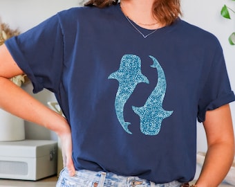 May include: A navy blue t-shirt with a graphic of two blue whale sharks. The shirt has a relaxed fit and short sleeves.