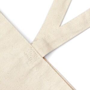 May include: Close-up of the top of a natural-coloured canvas tote bag with a reinforced seam where the straps meet the bag.