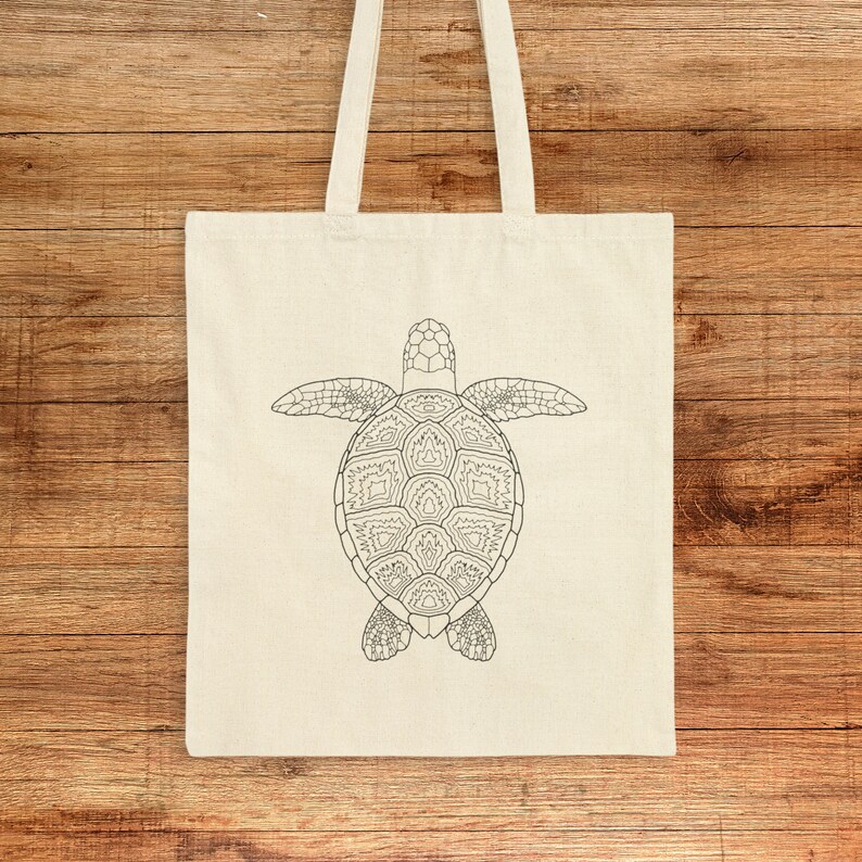 May include: A white canvas tote bag featuring a black line drawing of a sea turtle on the front. The turtle is facing downwards with its shell visible.