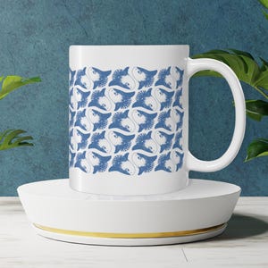 May include: White ceramic mug with a blue and white pattern of stylized fish. The pattern is repeated across the entire mug.