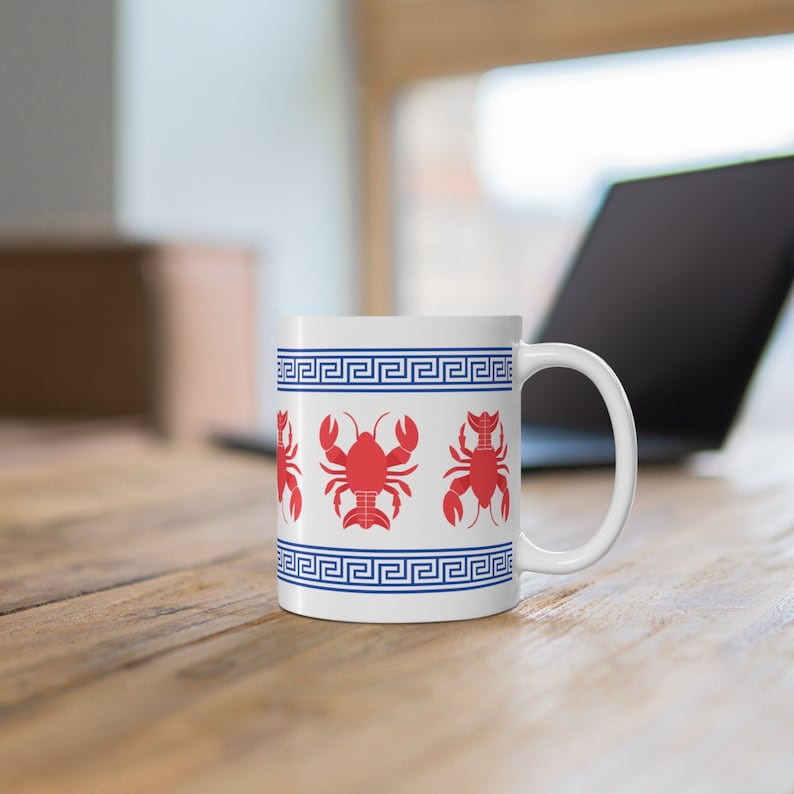 Pode incluir: Caneca de cer&acirc;mica branca com um design de chave grega azul e branca e ilustra&ccedil;&otilde;es de lagostas vermelhas.