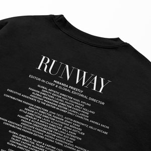 Pode incluir: Camiseta preta com texto branco que diz "RUNWAY" e lista os nomes e t&iacute;tulos da equipe da revista. O texto inclui "Editor-in-Chief & Global Editorial Director Miranda Priestly".