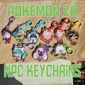 May include: A collection of nine acrylic keychains featuring various cartoon characters with colorful hair and outfits, each attached to a matching plastic clasp. The text POKEMON ZA NPC KEYCHAINS is displayed in green block letters.