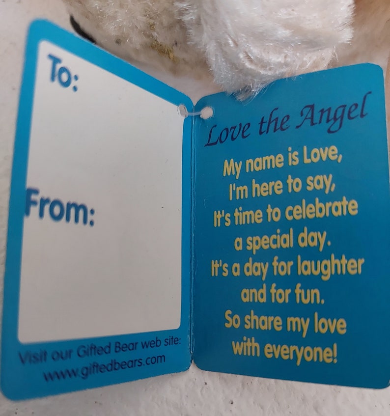 May include: A blue and yellow card with the text "Love the Angel" and a poem about love and celebration. The card has blank spaces for "To:" and "From:" and a website address at the bottom.