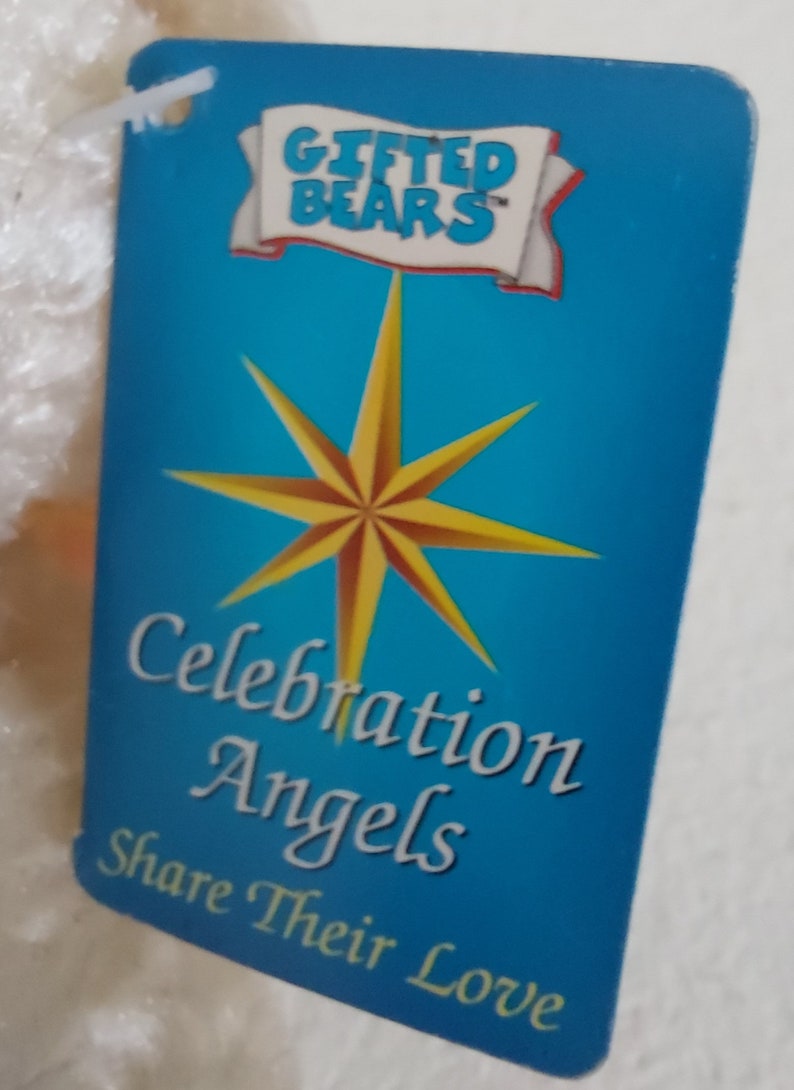 May include: A blue tag with a white star and the text "Gifted Bears" in a white banner. The text "Celebration Angels Share Their Love" is written in white on the tag.