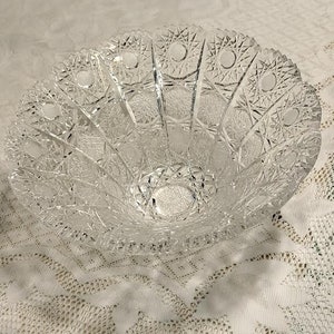 May include: A clear glass bowl with a cut glass design. The bowl has a scalloped edge and a wide, shallow base.