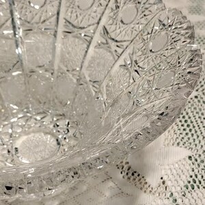 May include: A clear glass bowl with a cut glass design. The bowl has a scalloped edge and is made of crystal.