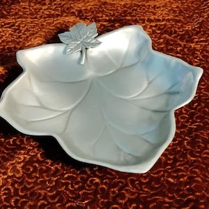 May include: A silver leaf-shaped serving dish with a raised leaf design. The dish has a smooth, shiny finish and is perfect for serving snacks or appetizers.
