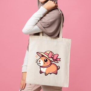 K&ouml;nnte beinhalten: Eine wei&szlig;e Einkaufstasche mit einem Cartoon-Hamster, der einen rosa Hut und eine Schleife tr&auml;gt. Der Hamster ist braun und wei&szlig; und hat eine rosa Nase.