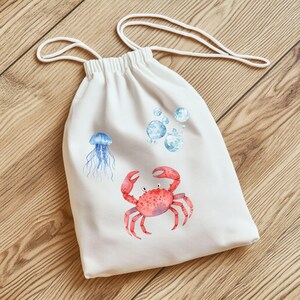 May include: White drawstring bag with a red crab, a blue jellyfish, and blue watercolor bubbles printed on it.