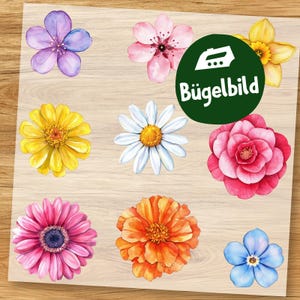 Op de afbeelding: Een verzameling kleurrijke bloemen opstrijkpatches. De patches tonen verschillende bloemontwerpen, waaronder een paarse bloem, roze kersenbloesem, gele narcis, witte madelief, roze camelia, roze gerbera, oranje zinnia en blauwe vergeet-mij-nietje. Een groene cirkel met de tekst "Bügelbild" is ook aanwezig.