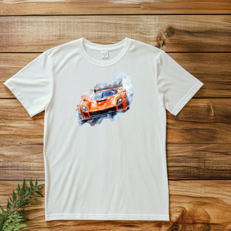 Puede incluir: Camiseta blanca con una ilustraci&oacute;n de acuarela de un coche de carreras naranja con humo saliendo de los neum&aacute;ticos.