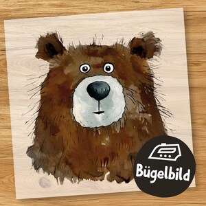 May include: Iron-on transfer of a cartoon brown bear with a white muzzle and big eyes. The bear is looking directly at the viewer. The image is on a light wood background with the text "Bügelbild" in black.