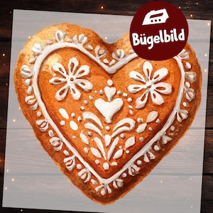 Może przedstawiać: Ilustracja piernika w kształcie serca z białymi wzorami z lukru przedstawiającymi kwiaty i zawijasy. Ciemnoczerwona okrągła odznaka w prawym górnym rogu zawiera białą ikonę żelazka oraz napis Bügelbild wykonany białą czcionką.
