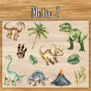 May include: Watercolor illustrations of various dinosaurs, a palm tree, and a volcano on a wooden background. The text "Motiv 2" is at the top. The dinosaurs include a T-Rex, Brontosaurus, and Triceratops.
