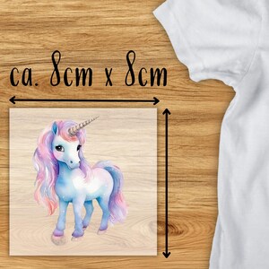 May include: A square image featuring a watercolor illustration of a unicorn with a blue body, pink and purple mane and tail, and a silver horn. The image is approximately 3.15 inches by 3.15 inches. The text "ca. 8cm x 8cm" is above the image.