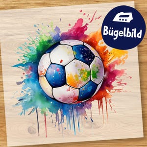 Pode incluir: Um design colorido de bola de futebol com salpicos de tinta aquarela em várias cores. A bola é branca, azul e preta. Um círculo azul com o texto "Bügelbild" está no canto superior direito.