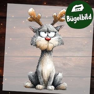 Könnte beinhalten: Ein grimmiger Cartoon-Katze mit Rentiergeweih, roter Nase und gerunzelter Stirn. Die Katze ist grau und weiß, mit flauschiger Brust und ernstem Gesichtsausdruck. Ein grüner Kreis mit dem Text "Bügelbild" befindet sich in der oberen rechten Ecke.